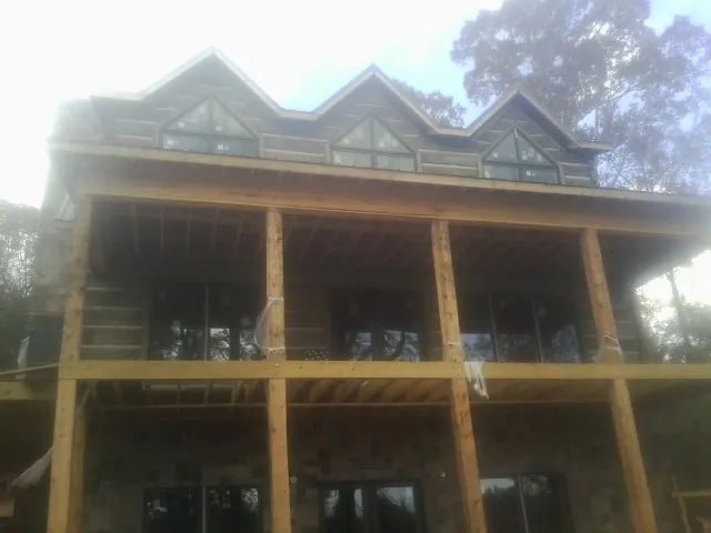 Dormers and porch framing on a large log home under construction — Roof Coating work by our crew in Cromwell