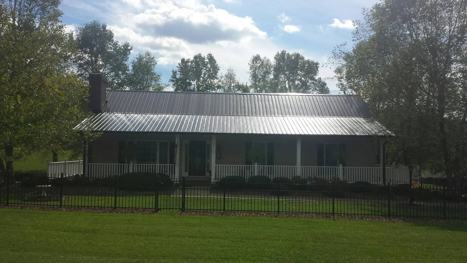 Gray metal roof on a brick ranch with a full width front porch — Gutter Guard Installation work by our crew in Cromwell